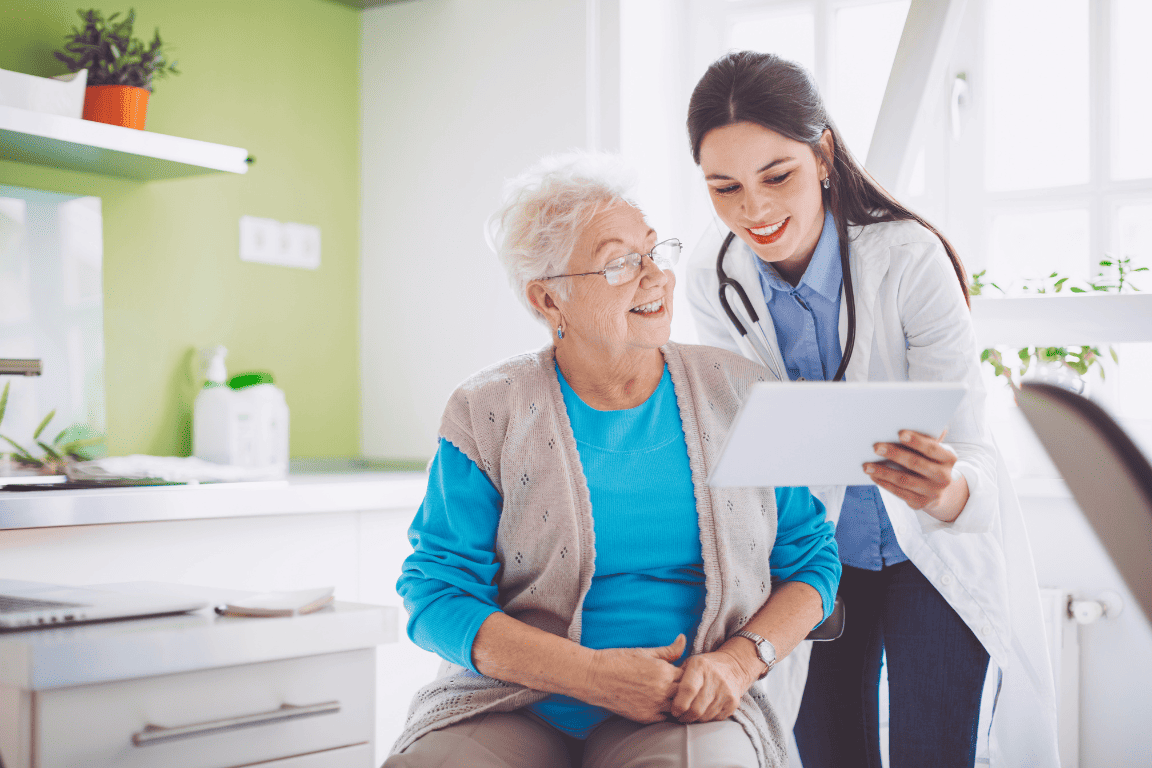 Uma enfermeira está conversando com uma idosa em um tablet.