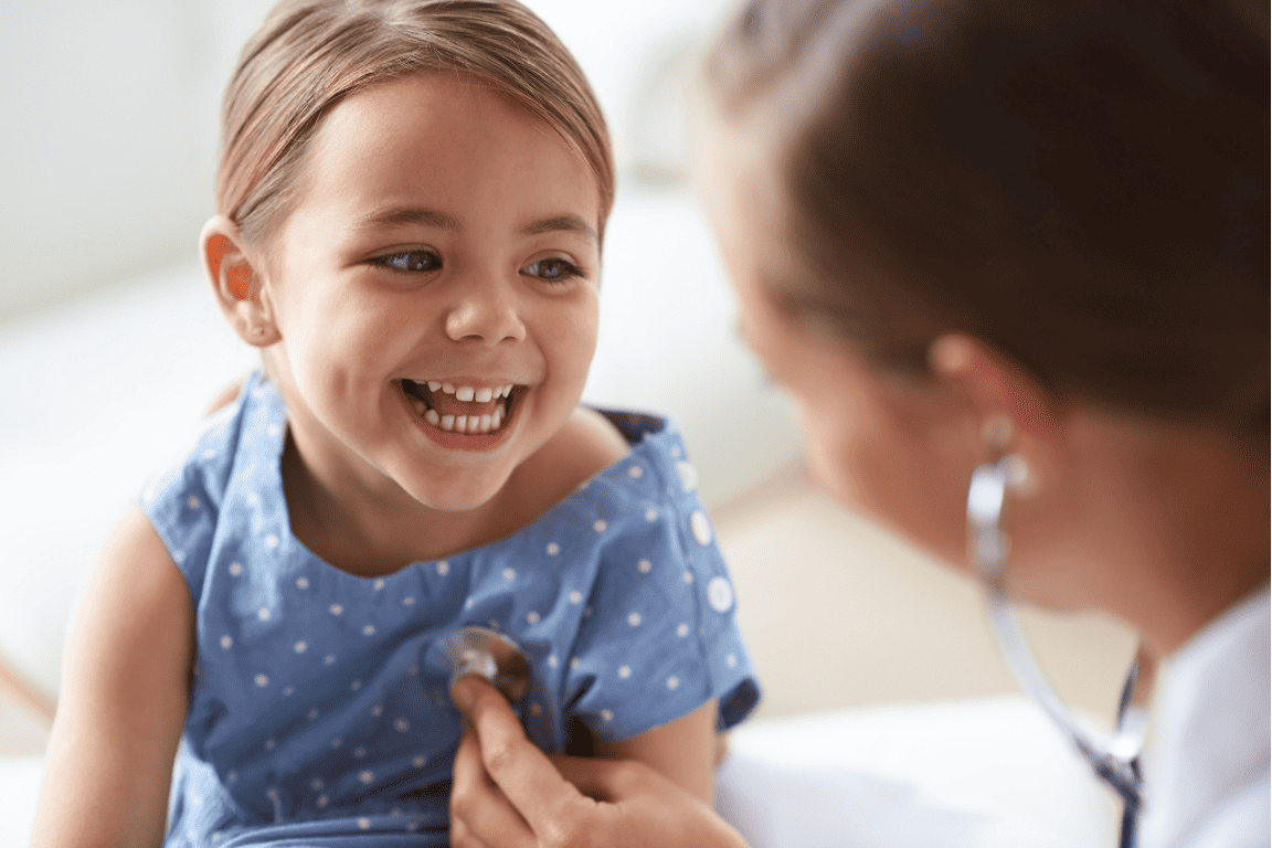 Uma jovem está sorrindo enquanto é examinada por um médico.