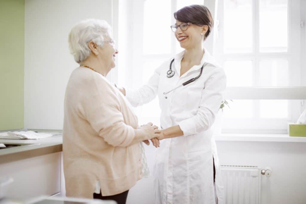 Um médico aperta a mão de uma senhora idosa.