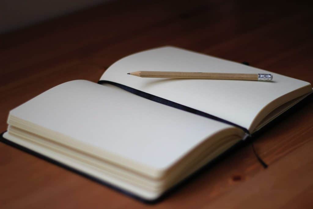 Um caderno aberto com um lápis em cima.